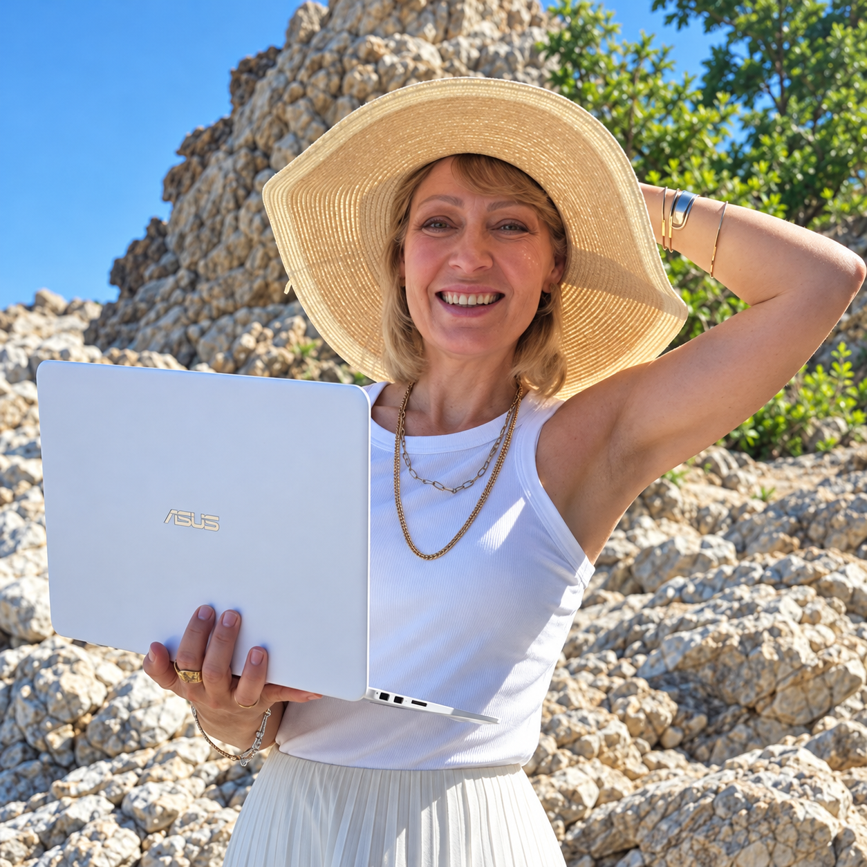 Claudia-Ayda Stahl mit Laptop und Sonnenhut vor Felsen in Alanya